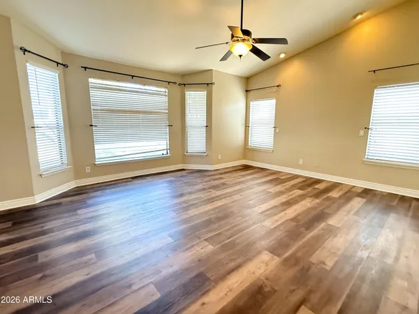 a view of an empty room with a window and wooden floor