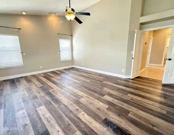 a view of empty room with wooden floor and fan