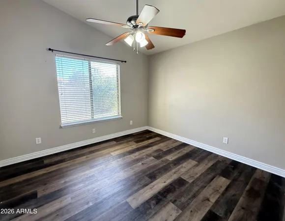 a view of an empty room with window and wooden floor