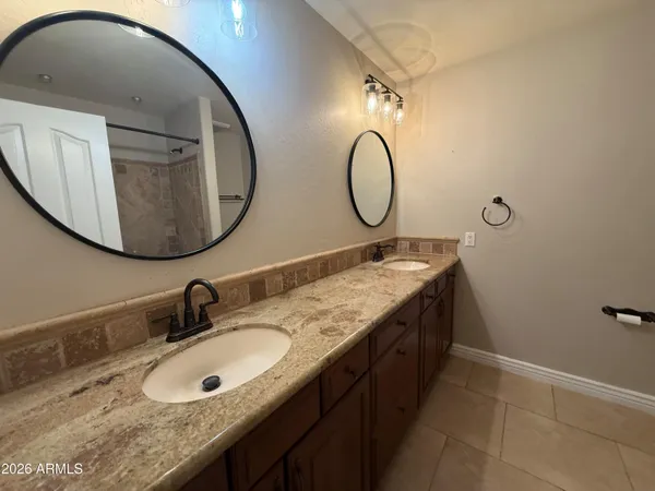 a bathroom with a granite countertop double vanity and a mirror