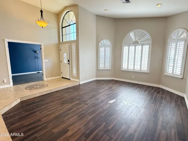 a view of an empty room with wooden floor fan and window