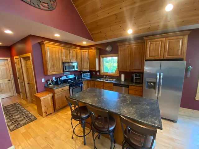 a kitchen with stainless steel appliances granite countertop table chairs and a refrigerator