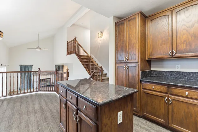 a kitchen with kitchen island granite countertop a stove and a wooden cabinets
