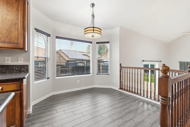 a view of a room with wooden floor a ceiling fan and windows
