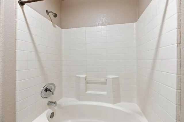 an empty room with chandelier fan and windows