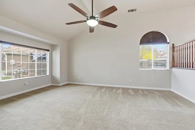 an empty room with windows and fan
