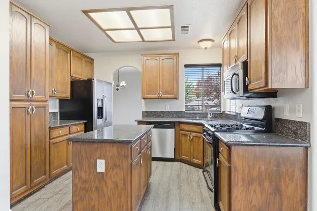 a kitchen with stainless steel appliances granite countertop a sink stove and refrigerator