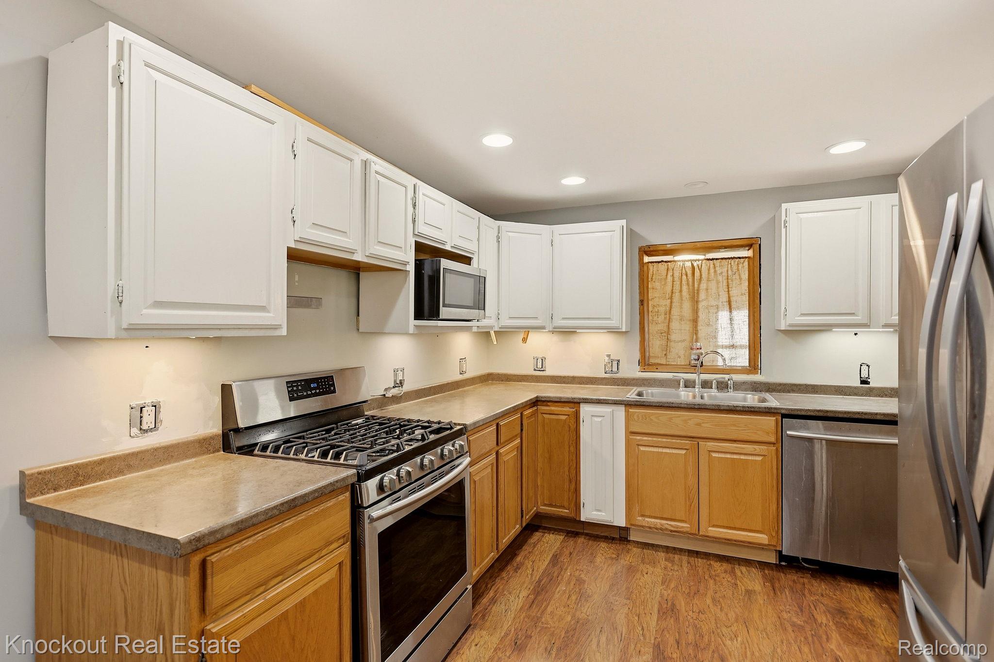 8811 Van Cleve Road Vassar, MI 48768 - Photo 13 of 39 Kitchen featuring wood-finish flooring, two-tone cabinetry, stainless steel appliances, a built-in microwave, and recessed lighting