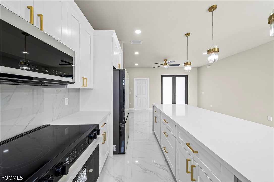 2919 9th Street Southwest Lehigh Acres, FL 33976 - Photo 8 of 29 a large kitchen with kitchen island white cabinets and stainless steel appliances