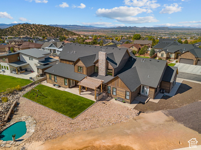 1192 East Ashdown Road Cedar City, UT 84721 - Photo 16 of 96 Expansive property featuring a multi-level wood-clad exterior, a stone-clad chimney, a covered patio with a pergola, a manicured lawn area, and a rock-lined pond