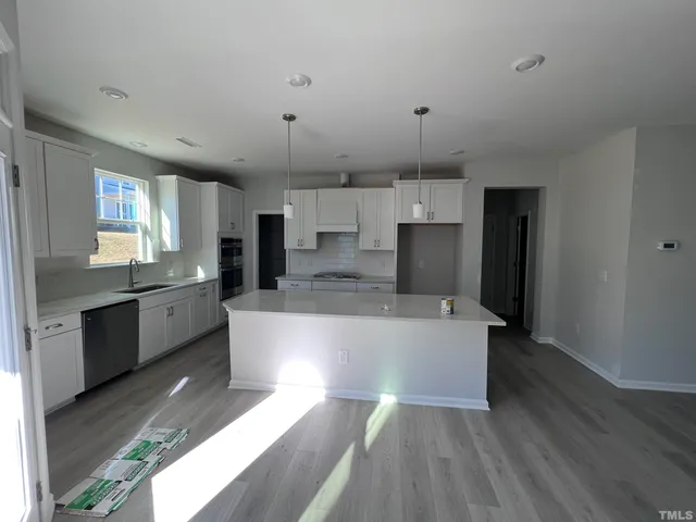 a large kitchen with a large counter top stainless steel appliances and cabinets