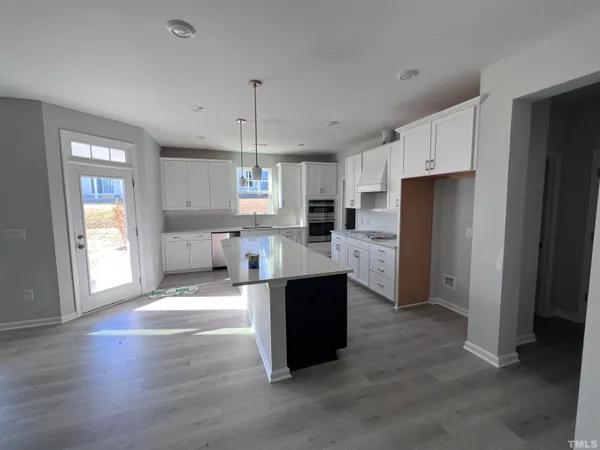 a large kitchen with stainless steel appliances kitchen island granite countertop a refrigerator and a sink