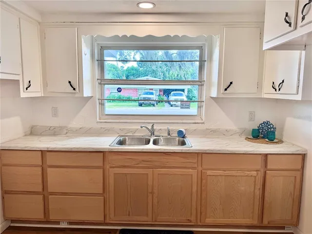 a kitchen with white cabinets and window