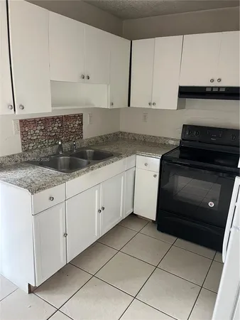 a kitchen with granite countertop white cabinets and stainless steel appliances