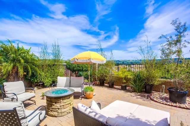 a view of a patio with couches table and chairs under an umbrella with a fire pit