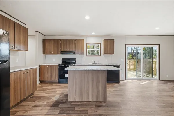 a kitchen with stainless steel appliances granite countertop a stove a sink dishwasher and a refrigerator with wooden floor