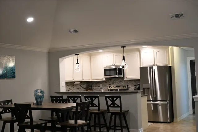 a kitchen with stainless steel appliances granite countertop a refrigerator a stove a sink a dining table and chairs