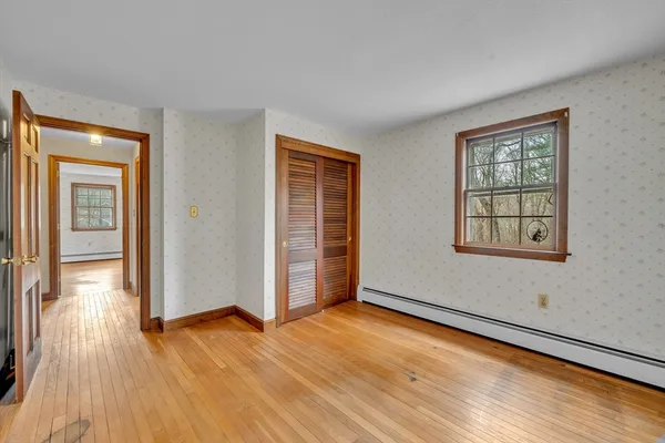 a view of an empty room with a window and wooden floor