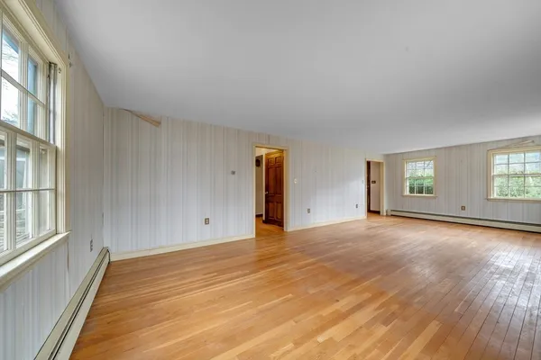a view of an empty room with wooden floor and windows