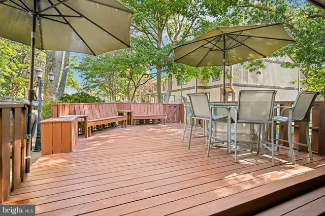 a view of a roof deck with table and chairs under an umbrella with wooden floor