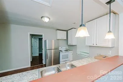 a kitchen with stainless steel appliances granite countertop a refrigerator a sink a stove and a wooden floors