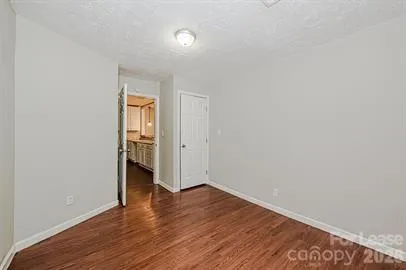 a view of an empty room with wooden floor and closet