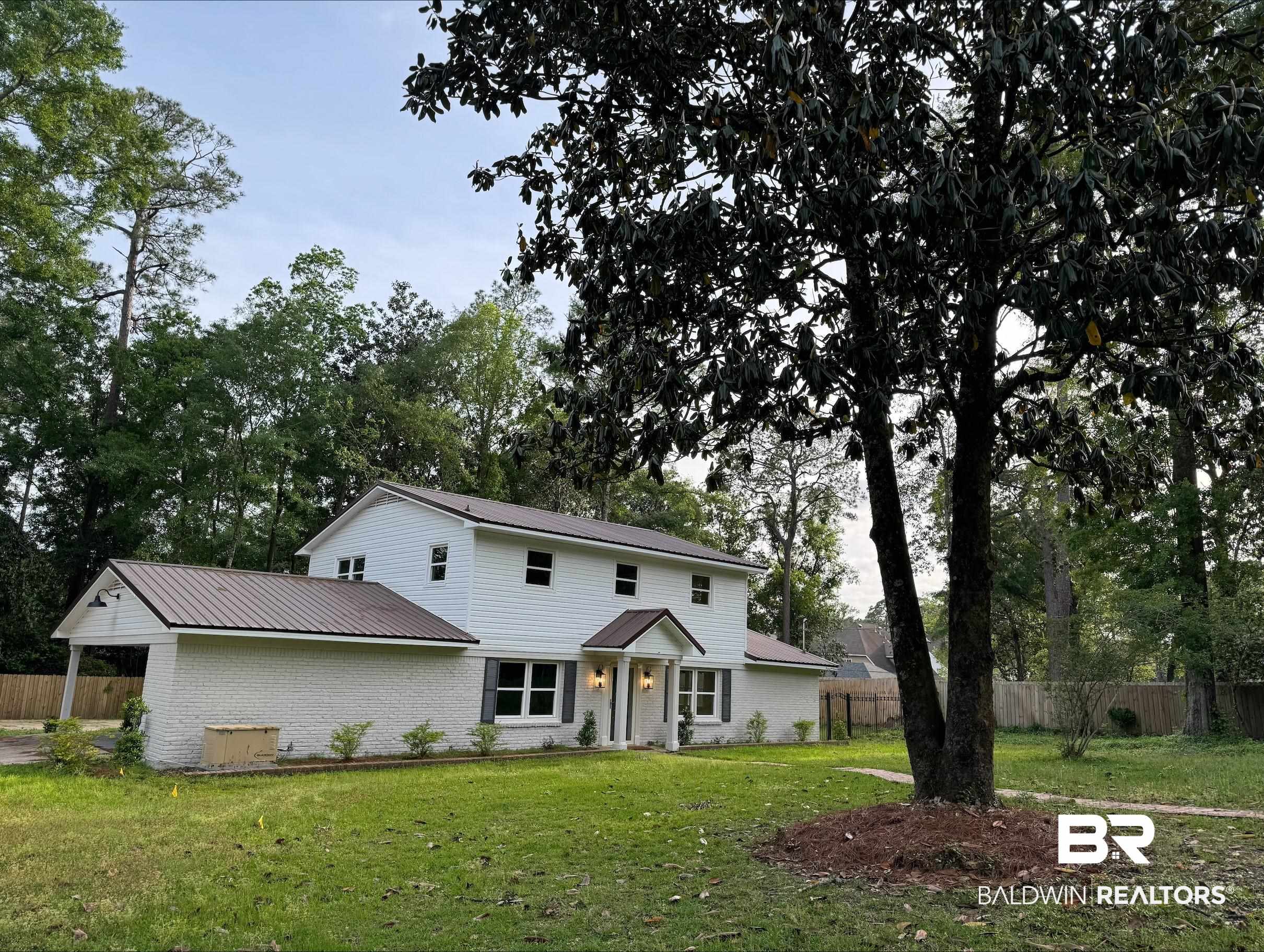 3933 Radnor Avenue Mobile, AL 36608 - Photo 31 of 36 View of front facade featuring a metal roof, brick siding, and view of wooded area.
