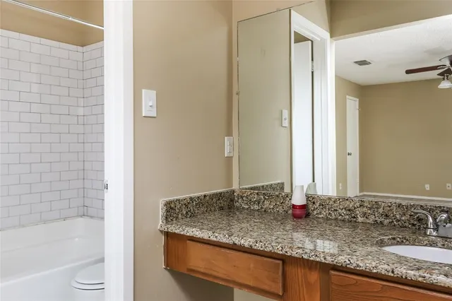 a bathroom with a granite countertop sink toilet and shower