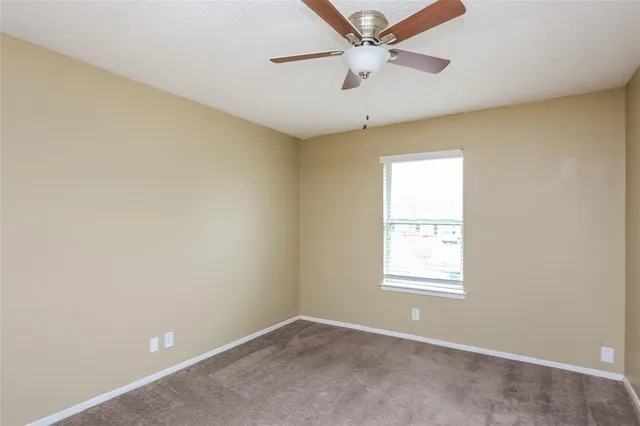 an empty room with a window and a fan