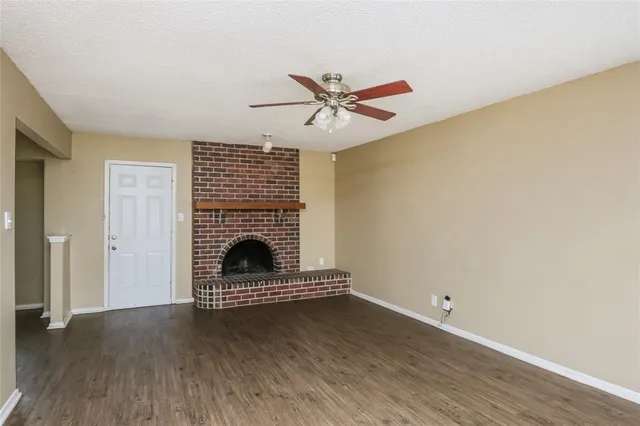 a view of a livingroom with wooden floor a ceiling fan and a window