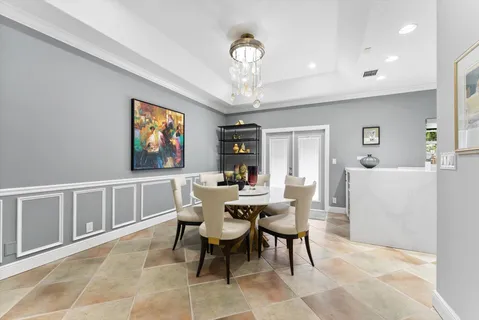 a dining room with furniture a rug a potted plant and a chandelier