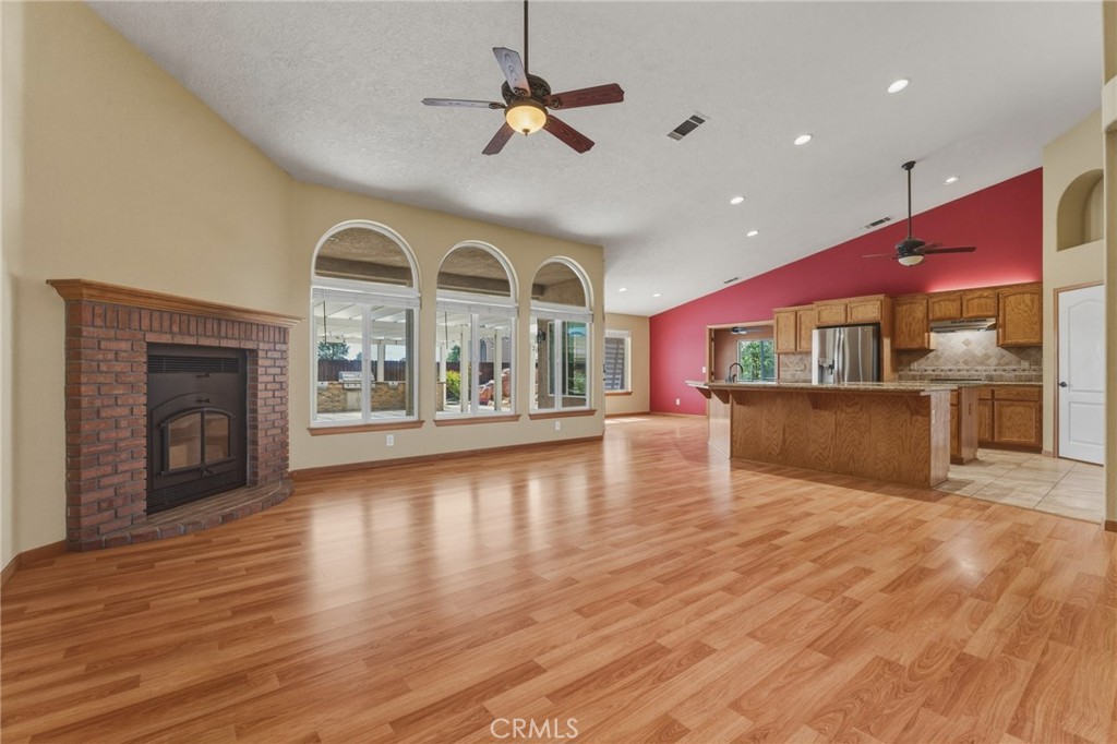 19501 Kinai Road Apple Valley, CA 92307 - Photo 11 of 49 an empty room with wooden floor a fireplace and a kitchen view