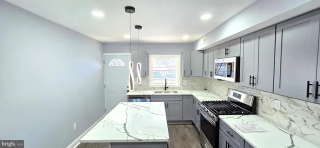 a kitchen with granite countertop white cabinets and stainless steel appliances