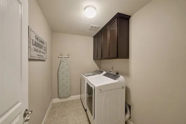 a bedroom with a bed a chandelier and a flat tv screen on the dresser