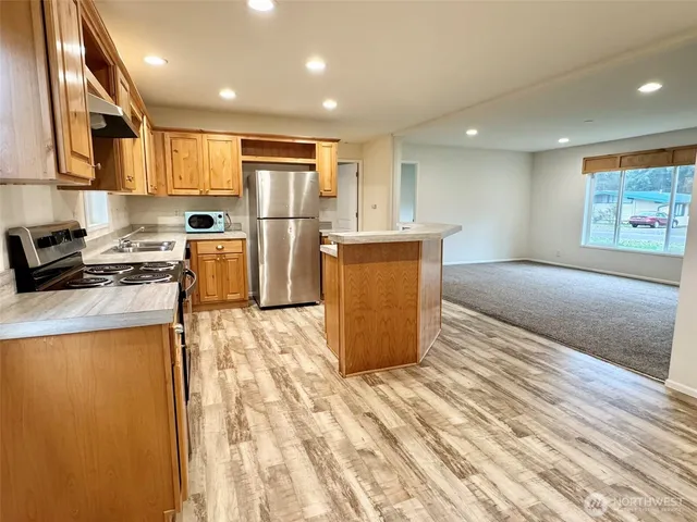 a kitchen with stainless steel appliances granite countertop a refrigerator a stove top oven a sink and dishwasher