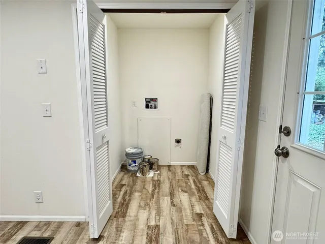a view of a hallway with wooden floor and a bathroom