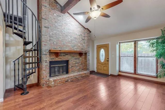 a view of an empty room with wooden floor fireplace and a window