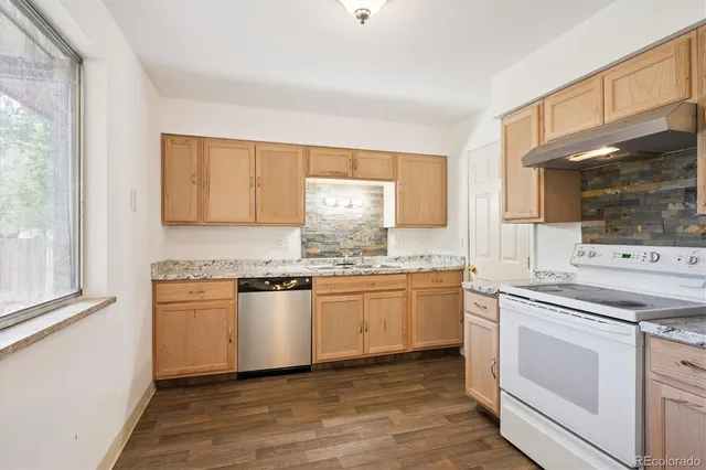 a kitchen with stainless steel appliances granite countertop a stove and white cabinets