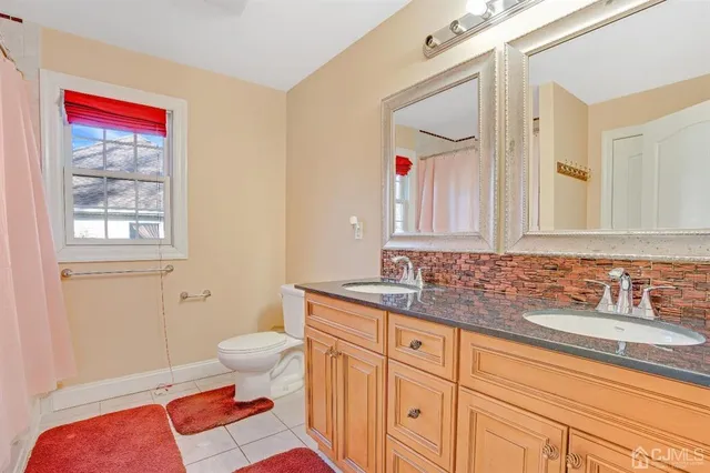 a bath room with a toilet a sink and a mirror