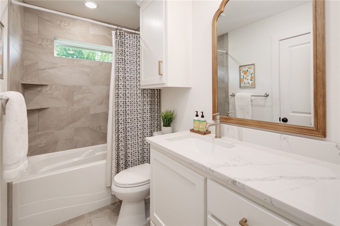 4700 Kensington Road Bryan, TX 77802 - Photo 20 of 31 Bathroom featuring a tub/shower combination with integrated shelving, a white vanity with a rectangular sink, a white countertop with grey veining, a wooden framed mirror, and recessed lighting