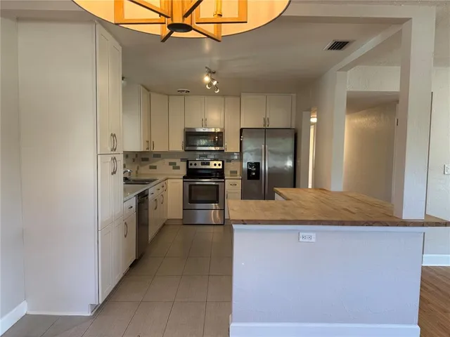 a kitchen with kitchen island a counter top space stainless steel appliances and cabinets