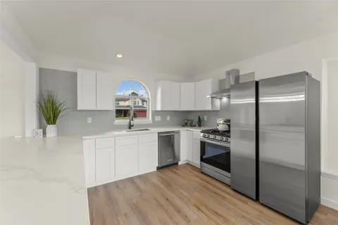 a kitchen with a sink stainless steel appliances and wooden floor