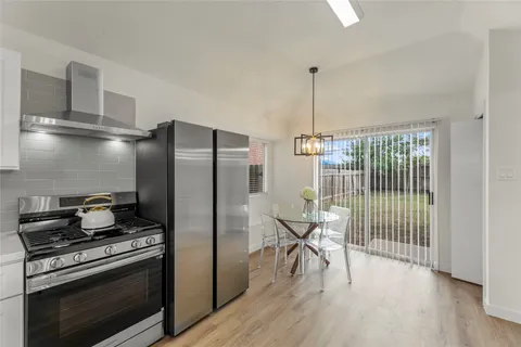 a kitchen with stainless steel appliances granite countertop a stove a refrigerator and a dining table