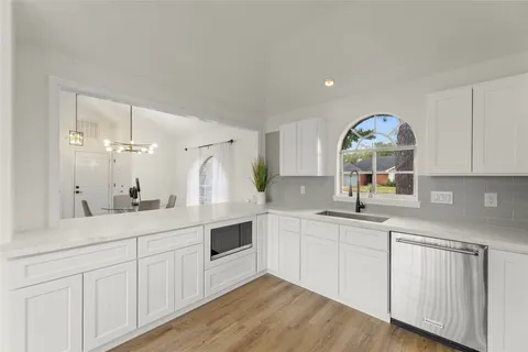 a kitchen with white cabinets and sink