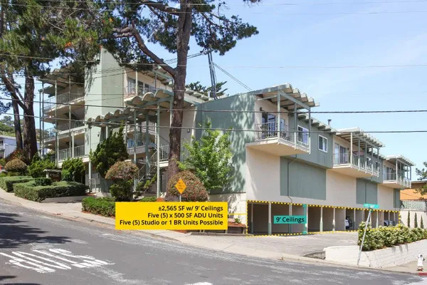 a front view of a building with a garden and trees