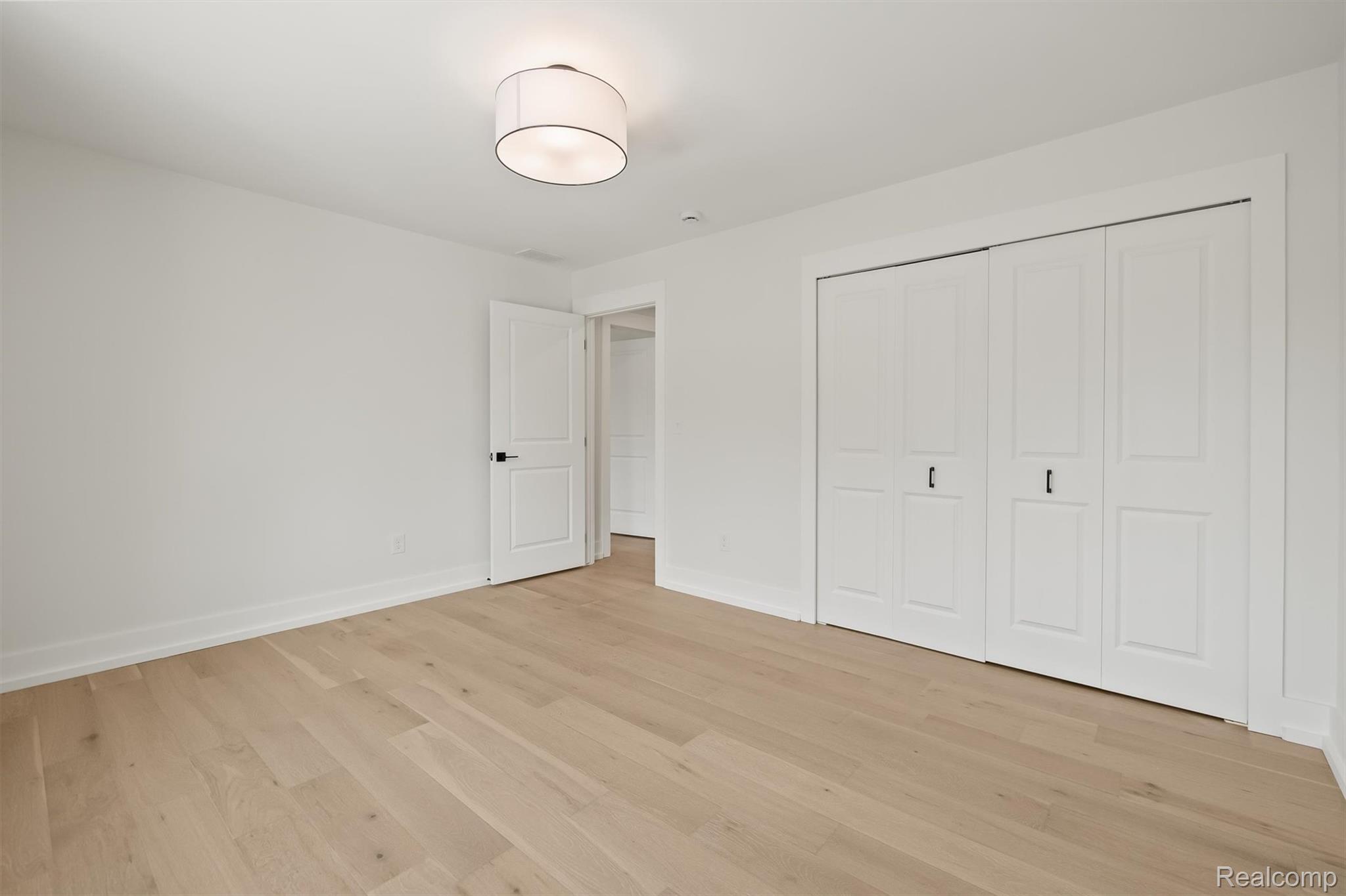 347 Highland Avenue Rochester, MI 48307 - Photo 38 of 59 Bright interior room with wood-finish flooring, white walls, and a contemporary flush-mount ceiling light
