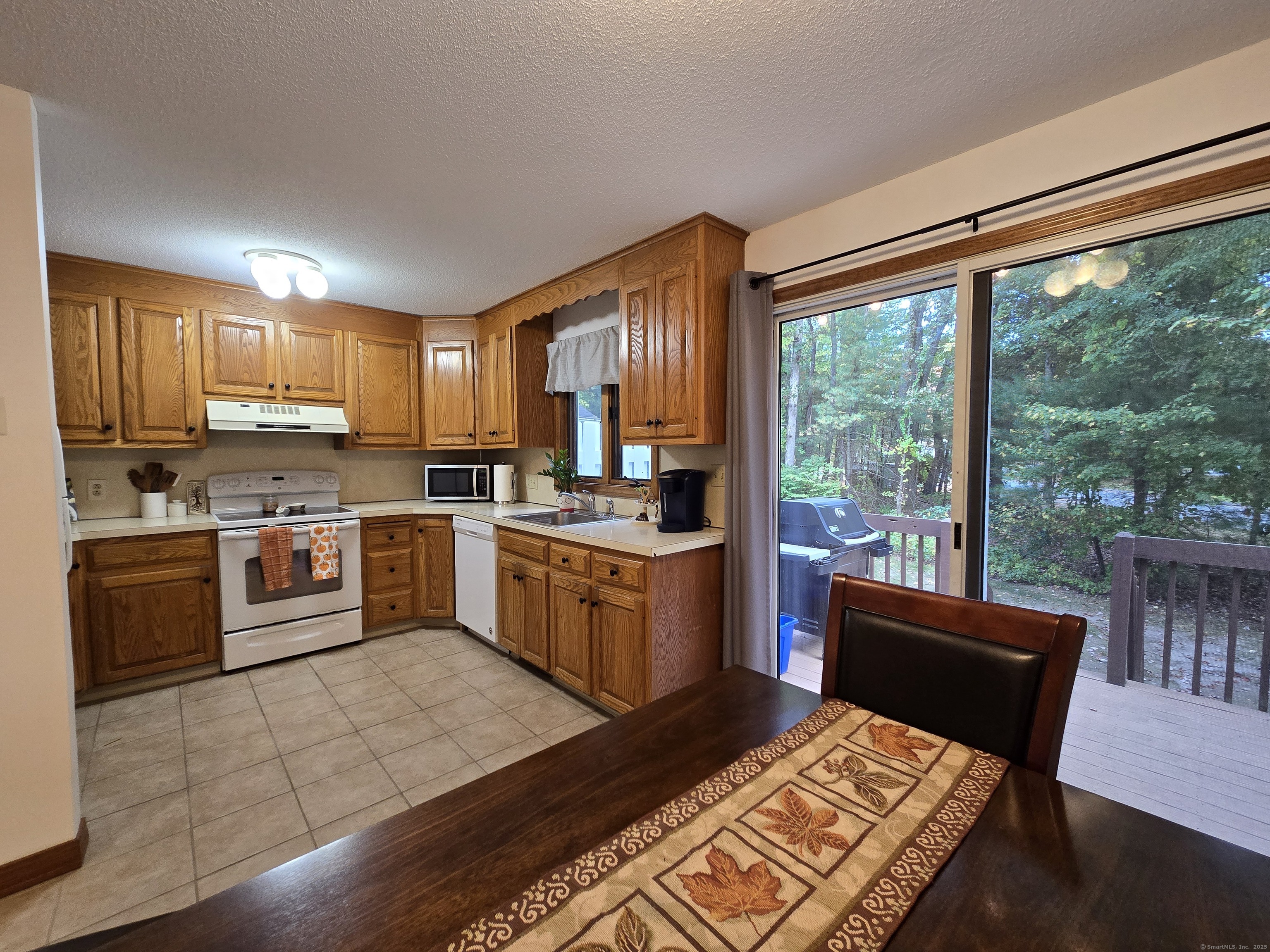85 Oldefield Farms, Unit 85 Enfield, CT 06082 - Photo 14 of 36 a kitchen with a stove a sink a microwave a dining table and chairs