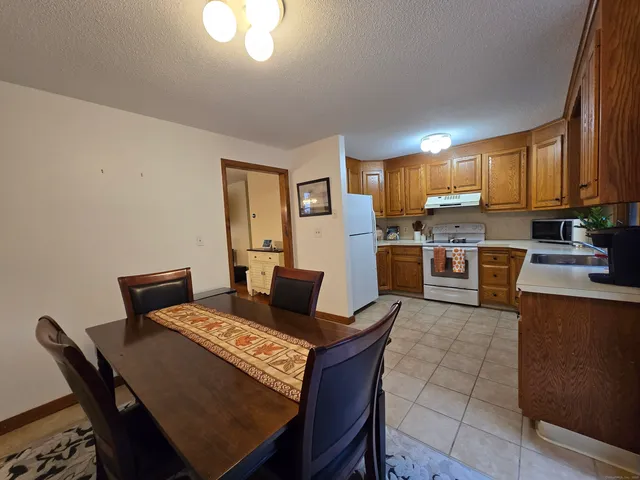 a living room with stainless steel appliances furniture a rug and a kitchen view