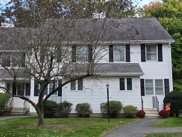 a view of a house with a yard and a large tree