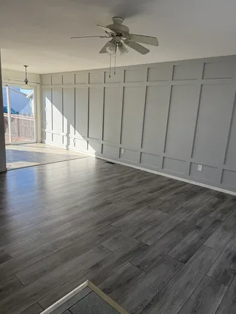 an empty room with wooden floor fan and windows